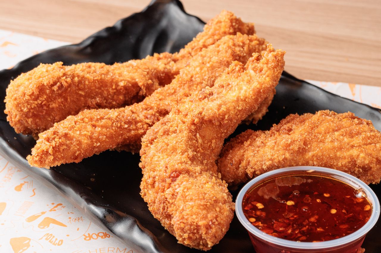 The Art of Drawing Readers In: Your attractive post title goes here Golden brown fried chicken strips served with a spicy chili dip on a black plate.